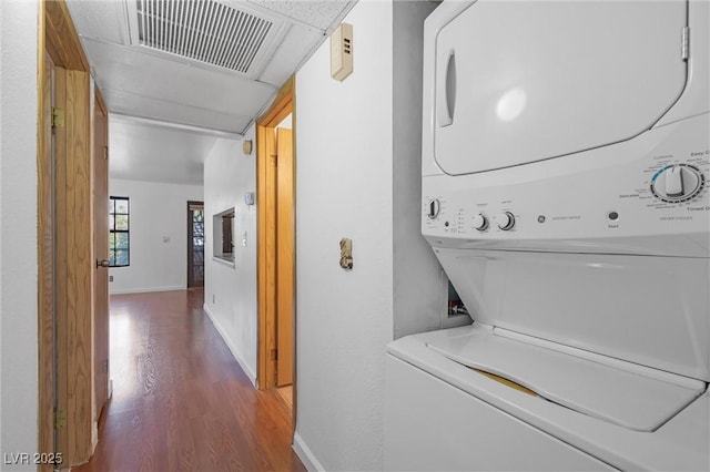 laundry area with stacked washing maching and dryer, baseboards, visible vents, and wood finished floors