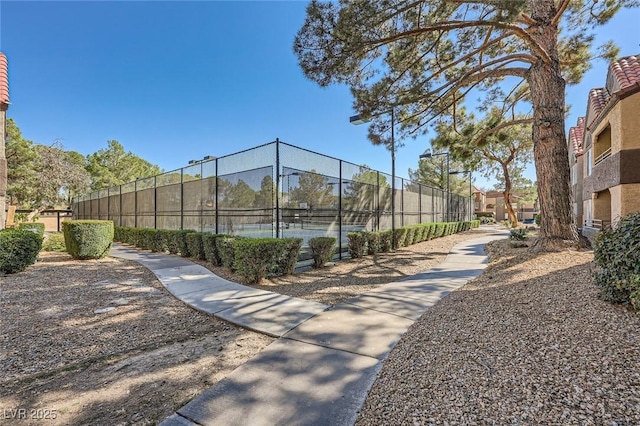 view of community featuring a tennis court and fence