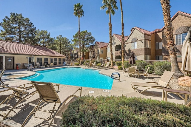 community pool with a patio area, a residential view, and fence