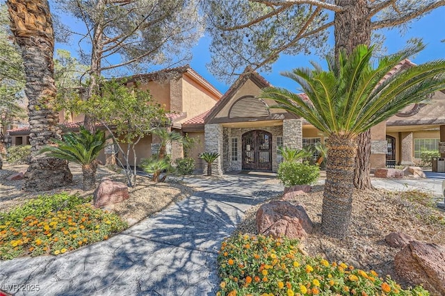 view of front facade featuring stone siding, a tile roof, and stucco siding