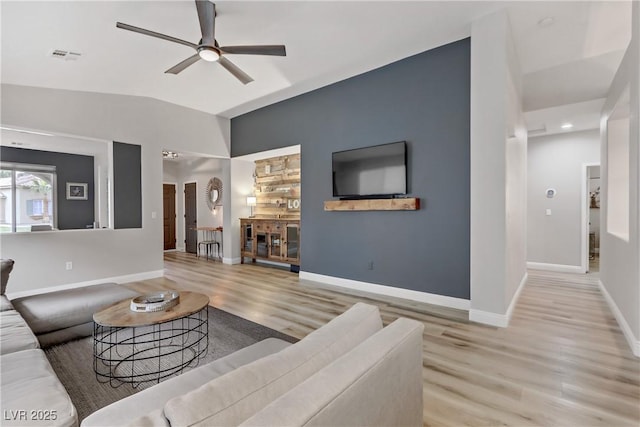 living area with ceiling fan, wood finished floors, visible vents, baseboards, and vaulted ceiling