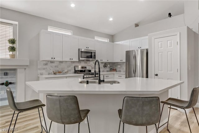 kitchen with decorative backsplash, a breakfast bar, stainless steel appliances, light countertops, and a sink