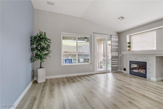 unfurnished living room featuring a fireplace, visible vents, vaulted ceiling, and wood finished floors