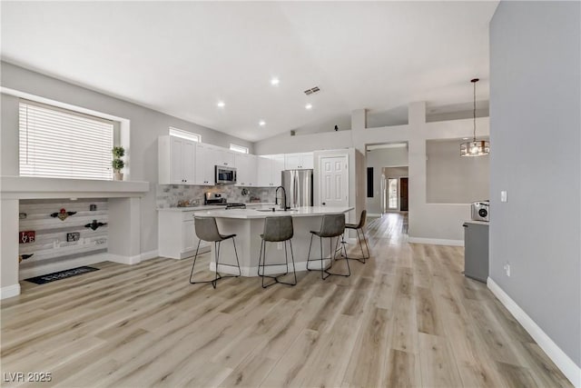 kitchen with stainless steel appliances, visible vents, backsplash, a sink, and a kitchen breakfast bar