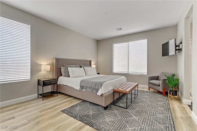 bedroom with light wood finished floors, visible vents, and baseboards