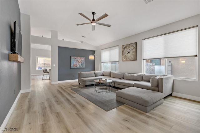 living room featuring lofted ceiling, light wood-style flooring, a ceiling fan, visible vents, and baseboards