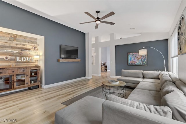 living area featuring a ceiling fan, vaulted ceiling, baseboards, and wood finished floors