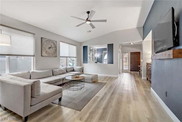 living area featuring light wood finished floors, visible vents, a ceiling fan, vaulted ceiling, and baseboards