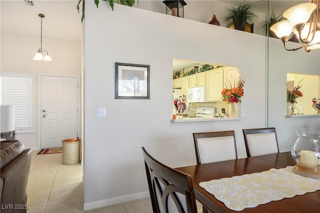 dining space with light tile patterned floors, baseboards, and a chandelier