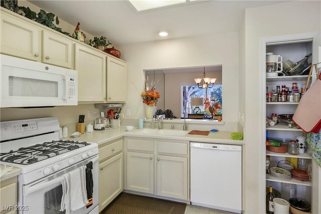 kitchen featuring a chandelier, light countertops, white appliances, and a sink