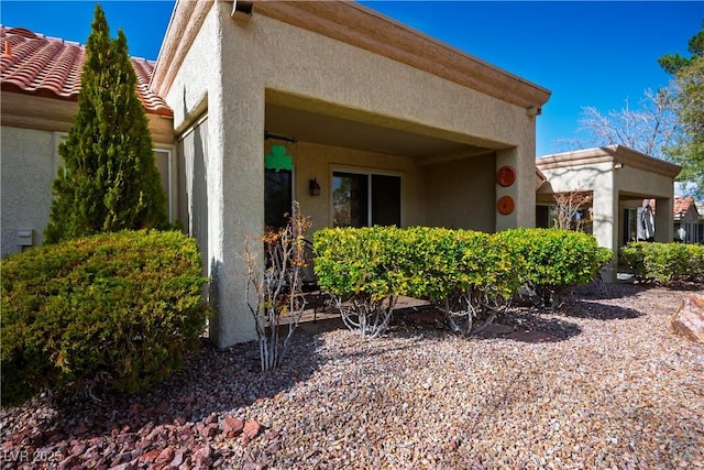 view of side of home featuring a tile roof and stucco siding