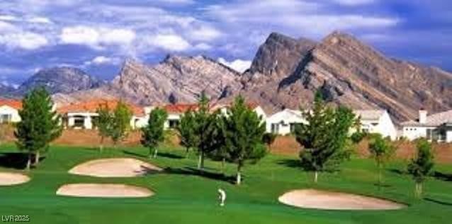 view of community with view of golf course, a mountain view, and a lawn