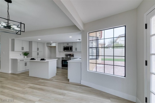 kitchen featuring a center island, baseboards, plenty of natural light, and stainless steel appliances