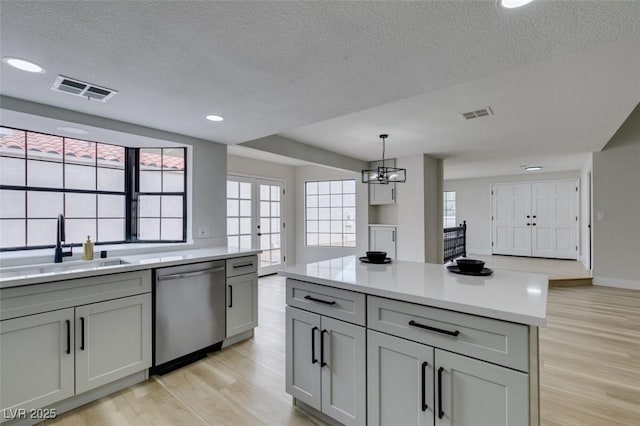 kitchen with visible vents, a sink, light countertops, and stainless steel dishwasher