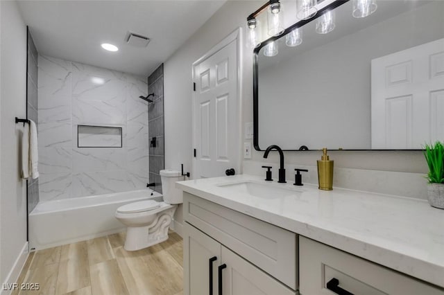 bathroom featuring visible vents, toilet, wood finished floors, shower / bath combination, and vanity