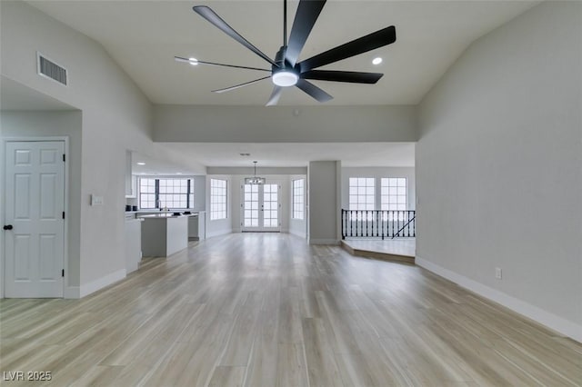 unfurnished living room with light wood-style flooring, plenty of natural light, baseboards, and visible vents