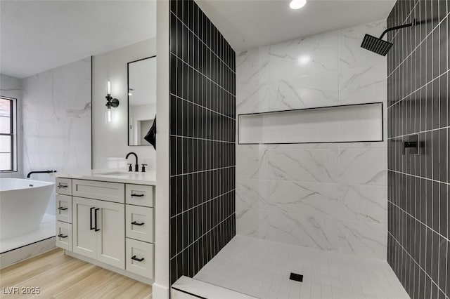 bathroom featuring a freestanding bath, walk in shower, wood finished floors, and vanity