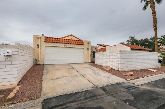 view of front of house with fence, a tiled roof, concrete driveway, stucco siding, and a garage