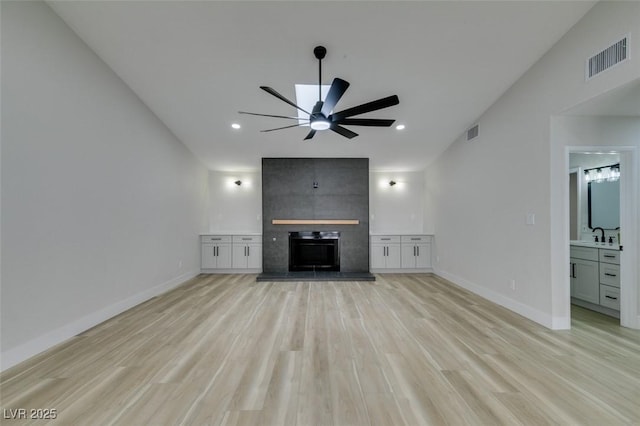 unfurnished living room with visible vents, a fireplace, light wood-type flooring, and baseboards