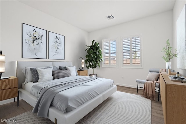 bedroom with baseboards, visible vents, and wood finished floors