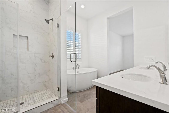 full bathroom with double vanity, a stall shower, a freestanding tub, and a sink