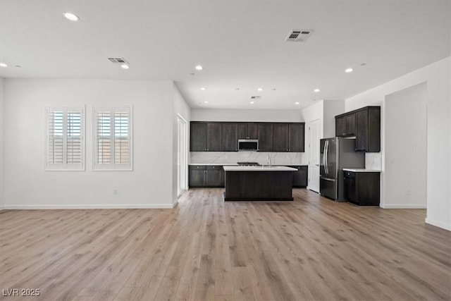 kitchen featuring light wood-style flooring, stainless steel appliances, visible vents, open floor plan, and light countertops