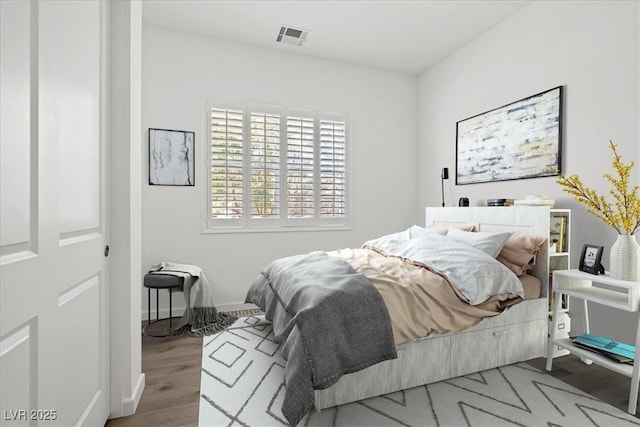 bedroom featuring wood finished floors, visible vents, and baseboards