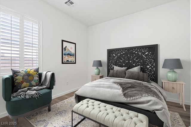 bedroom featuring baseboards, visible vents, and wood finished floors