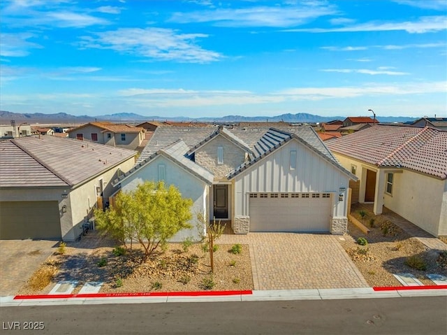 view of front of property with a garage, a residential view, decorative driveway, and a mountain view