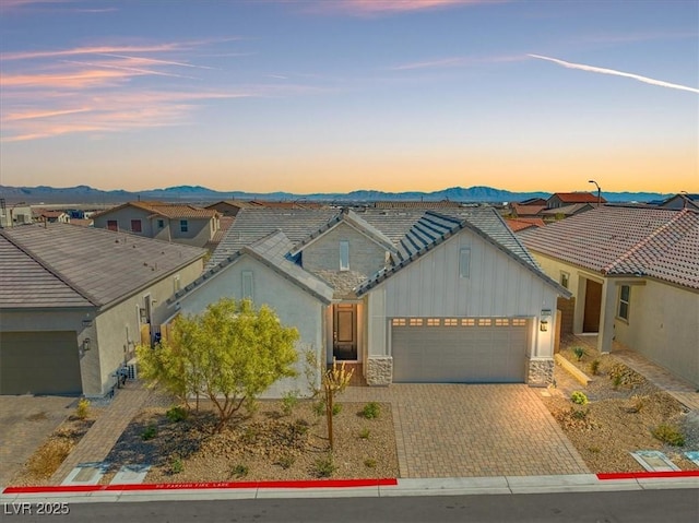 view of front of property featuring a mountain view, a garage, a tiled roof, decorative driveway, and a residential view