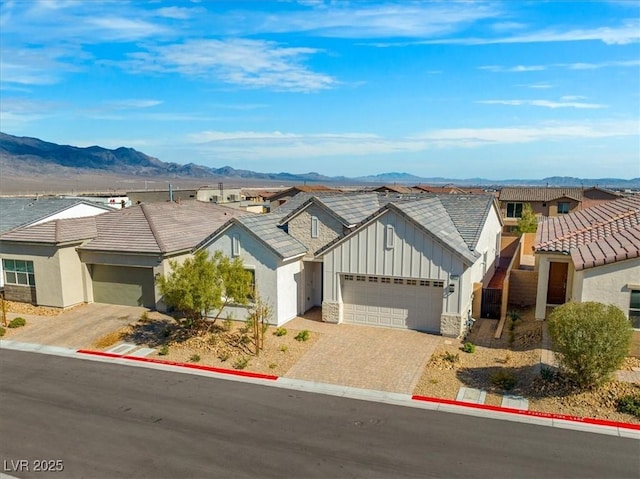 view of front of property with a residential view, an attached garage, decorative driveway, a mountain view, and board and batten siding