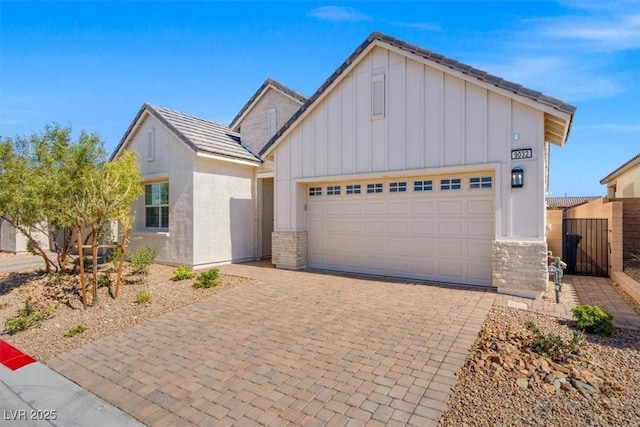 view of front of property featuring a garage, stone siding, decorative driveway, and board and batten siding