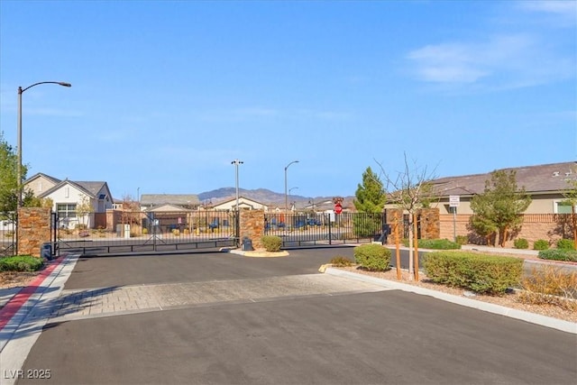 view of road with a gated entry, a residential view, a gate, and curbs