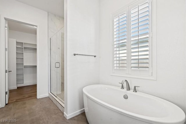 full bath featuring a freestanding bath, a spacious closet, a stall shower, and a healthy amount of sunlight