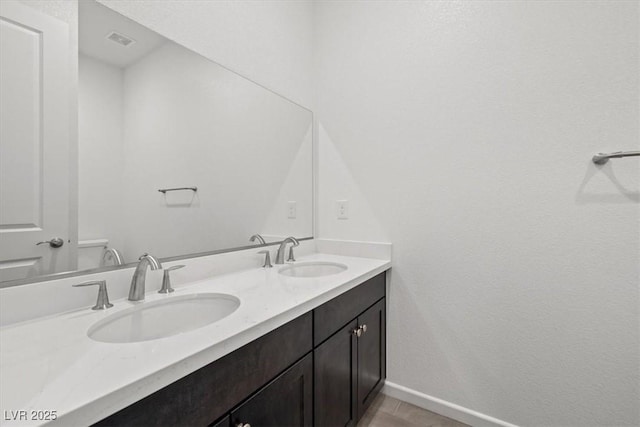 bathroom with visible vents, a sink, baseboards, and double vanity