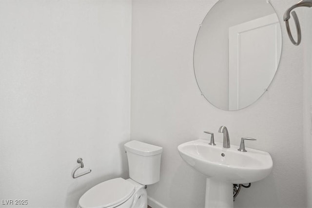 half bathroom featuring a sink, toilet, and baseboards