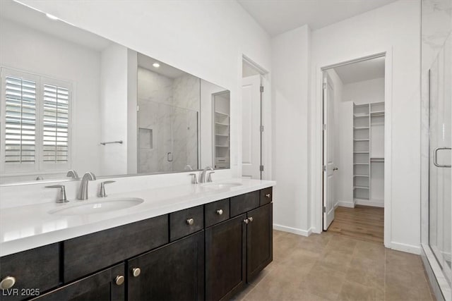 full bath featuring a stall shower, a sink, and a spacious closet