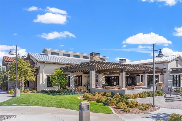 exterior space with a yard, stucco siding, a standing seam roof, metal roof, and a pergola