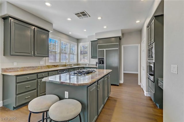 kitchen with light wood-style floors, visible vents, a sink, and built in appliances