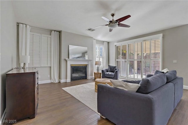 living area with baseboards, visible vents, wood finished floors, and a glass covered fireplace