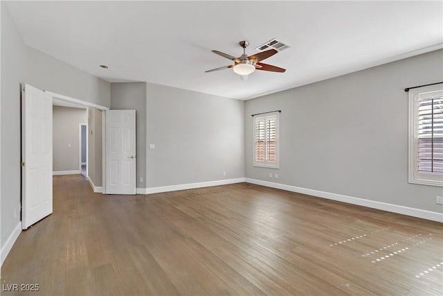 empty room featuring baseboards, wood finished floors, visible vents, and a ceiling fan