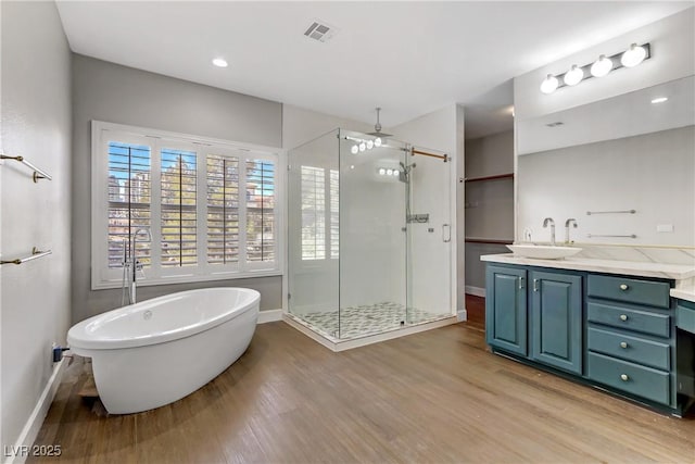 full bathroom featuring a stall shower, visible vents, wood finished floors, and a soaking tub