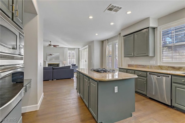 kitchen with appliances with stainless steel finishes, a glass covered fireplace, visible vents, and gray cabinetry