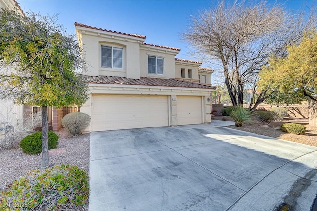 mediterranean / spanish home featuring concrete driveway, a tile roof, an attached garage, and stucco siding