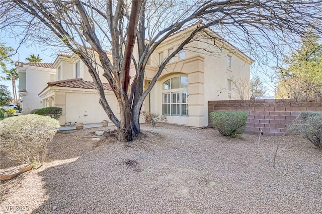 view of front of property featuring a tile roof, fence, and stucco siding