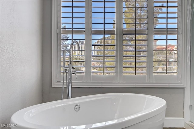 bathroom with a freestanding tub, a sink, and a textured wall