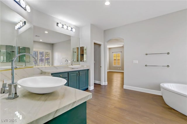 full bath with a freestanding tub, plenty of natural light, baseboards, and wood finished floors