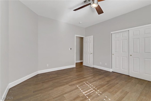 unfurnished bedroom featuring ceiling fan, a closet, baseboards, and wood finished floors