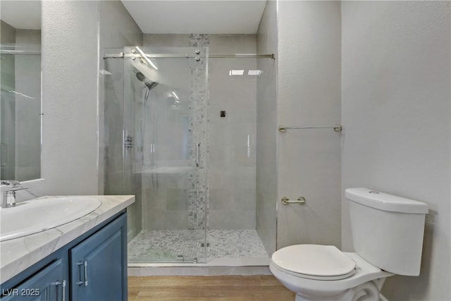 full bathroom featuring toilet, a stall shower, wood finished floors, and vanity