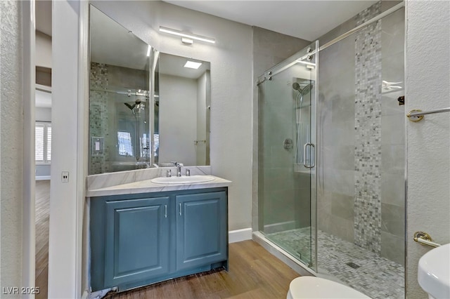 bathroom featuring a stall shower, wood finished floors, vanity, and baseboards